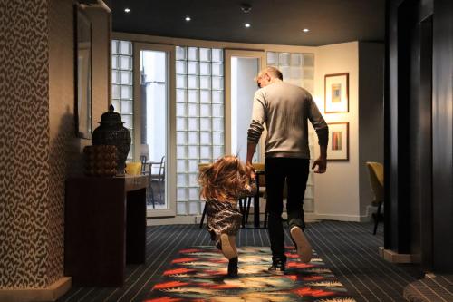 een man en een klein meisje die door een kamer lopen bij Le Pergolèse Paris Champs Elysées in Parijs