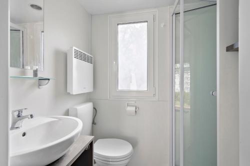 a white bathroom with a sink and a toilet at First Camp Hasmark Camping Resort & Cottages in Otterup