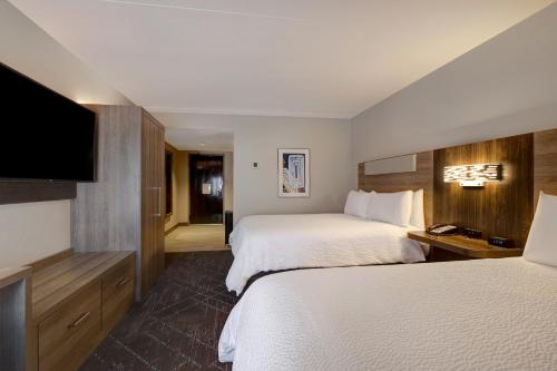 a hotel room with two beds and a flat screen tv at Holiday Inn Express & Suites - Kansas City KU Medical Center by IHG in Kansas City