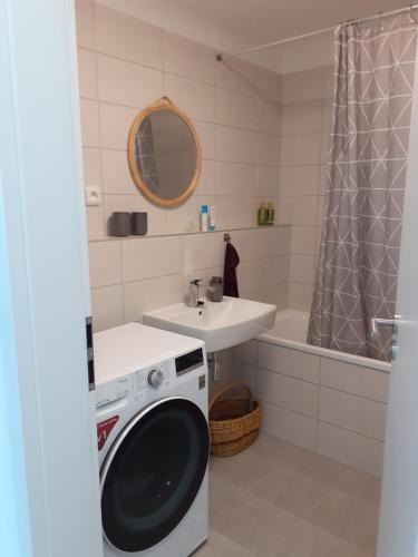 a washing machine in a bathroom with a sink and a tub at Nový byt s parkovaním na dosah Tatrám. in Poprad