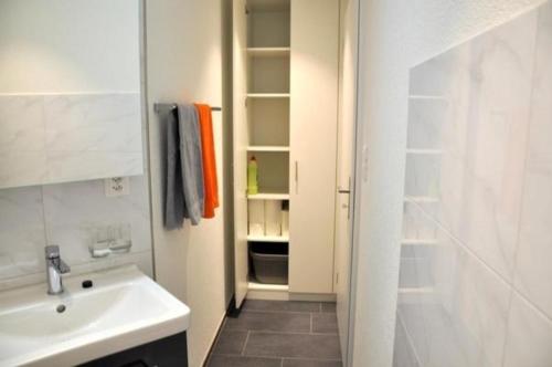 a white bathroom with a sink and a shower at Ferienwohnung Rätia mit Bodenseeblick in Wolfhalden 