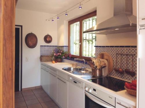 eine Küche mit weißen Schränken, einem Waschbecken und einem Fenster in der Unterkunft Casa Nespole, Familiennest mit Seesicht in Minusio