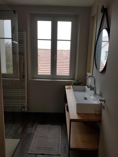 uma casa de banho com um lavatório, um espelho e uma janela em Gite le K'lin d'Oeil em Epfig