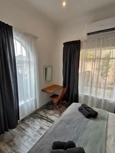 a bedroom with a bed and a desk and windows at 34 Hornbill Street in St Lucia