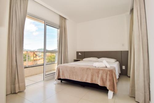 1 dormitorio con cama y ventana grande en 100m da Praia nos Ingleses, Condomínio com Piscina P2090, en Florianópolis