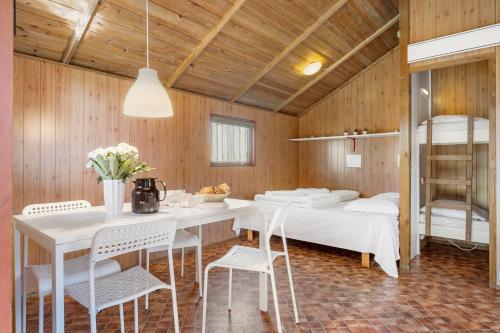 Cette chambre dispose d'une table, de chaises et de lits superposés. dans l'établissement First Camp Klim Strand - Nordvestkysten, à Fjerritslev