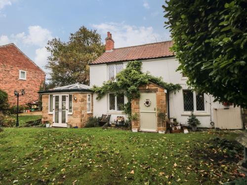 a white house with a porch and a yard at Laurel Cottage in Guisborough