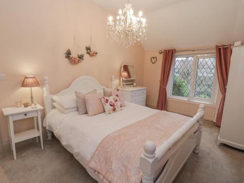 um quarto com uma cama branca e um lustre em Laurel Cottage em Guisborough