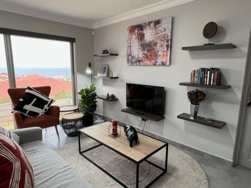 a living room with a couch and a tv and a table at Tulip On The Bay in Mossel Bay