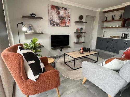 a living room with two chairs and a television at Tulip On The Bay in Mossel Bay