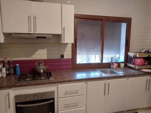 a kitchen with white cabinets and a sink and a window at حاتم للعقارات افران المغرب in Ifrane