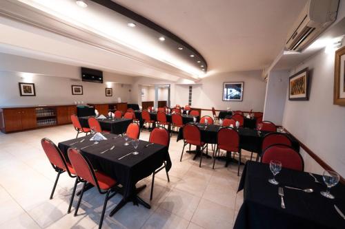 un salón de banquetes con mesas negras y sillas rojas en Hotel Ghala Salta en Salta