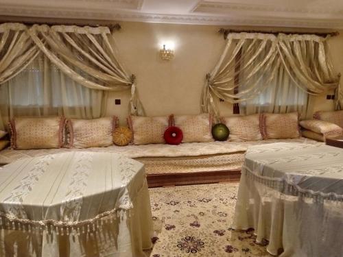 ein Wohnzimmer mit einem großen Sofa und Vorhängen in der Unterkunft حاتم للعقارات افران المغرب in Ifrane