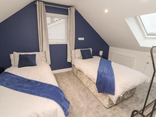 2 letti in una camera con pareti e finestre blu di Beckside House a Cockermouth