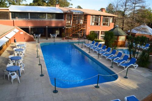 a swimming pool with chairs and a building at Rincon del Este Resort in Punta del Este