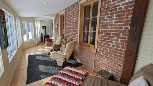 a living room with chairs and a brick wall at La Gentilhommière Motel et Suite A Vue sur Mer in Saint-Siméon