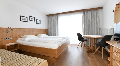 ヴァイトリングにあるGästehaus Luiseのベッド2台とデスクが備わるホテルルームです。