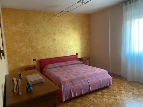 a bedroom with a red bed and a table with a table sidx sidx at La casa di Marta in Valeggio sul Mincio