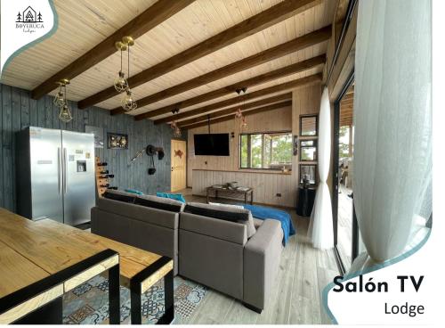 a living room with couches and a tv and a table at Maravillosas Vistas Boyeruca Lodge in Vichuquén