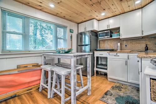 a kitchen with white cabinets and a table with stools at Walk to Beach Bright and Cozy Cape Cod Studio! in Dennis Port