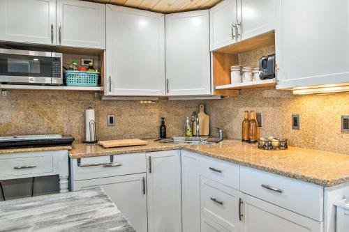 a kitchen with white cabinets and marble counter tops at Walk to Beach Bright and Cozy Cape Cod Studio! in Dennis Port