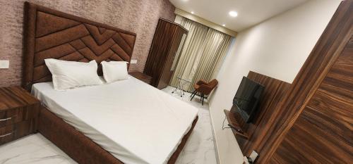 a small bedroom with a bed and a television at OVEL HOTEL (SKY VIEW) in Ludhiana