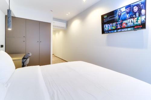 a bedroom with a white bed and a tv on the wall at AboV Athens in Athens