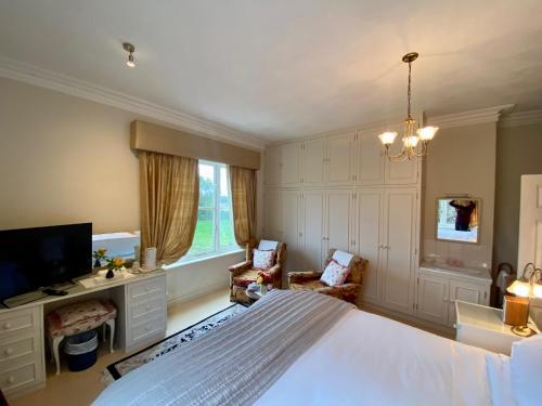 um quarto com uma cama, uma secretária e uma televisão em Golborne Manor Bed and Breakfast em Chester
