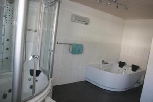 La salle de bains blanche est pourvue d'une baignoire et d'une douche. dans l'établissement Bädli im Munzenriet, à Wildhaus