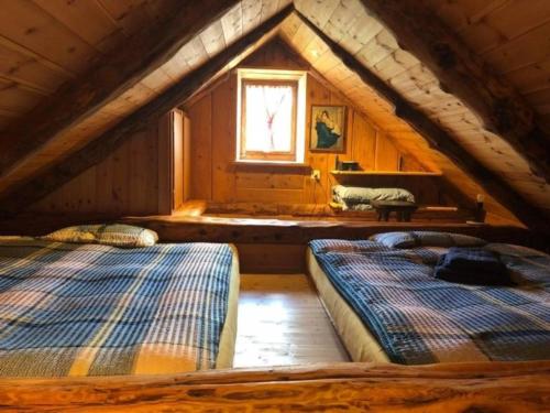 two beds in a attic room with a window at Rustico "Casi Hütte" in Bosco Gurin