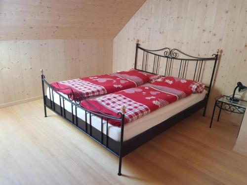 a bedroom with a bed with red and white sheets at Alphütte Sammligen Hilfernpass in Flühli