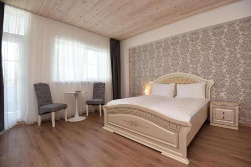 1 dormitorio con 1 cama blanca, mesa y sillas en Floros simfonija Jūros en Šventoji