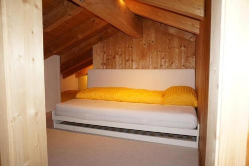 uma cama num pequeno quarto com tectos em madeira em Casa SagognLaax em Sagogn