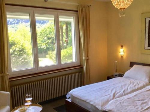 1 dormitorio con cama y ventana grande en "CASA ELENA -Tegna" die Ruheoase in grossem mediterranem Garten en Tegna