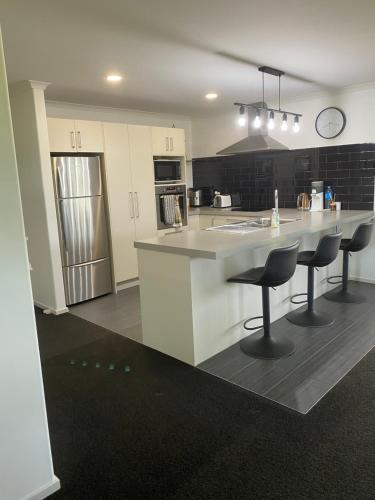 a kitchen with a counter and two bar stools at Beautiful Home with Rural Views in Kihikihi