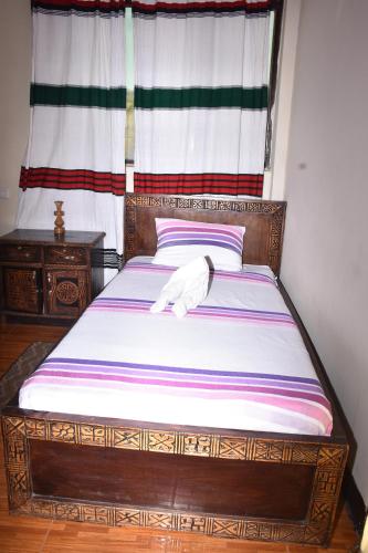 a wooden bed in a room with a window at Torpedo Hotel in Lalībela