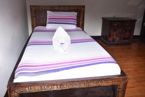 a bed with a white cat laying on top of it at Torpedo Hotel in Lalībela