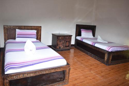 two beds in a room with wooden floors at Torpedo Hotel in Lalībela