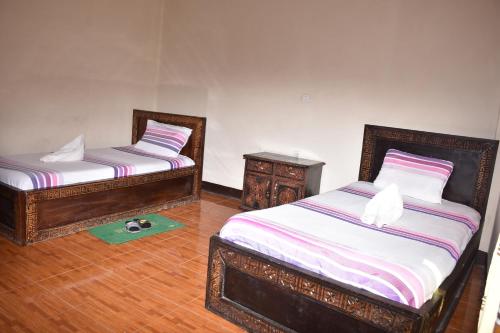 two twin beds in a room with a green rug at Torpedo Hotel in Lalībela