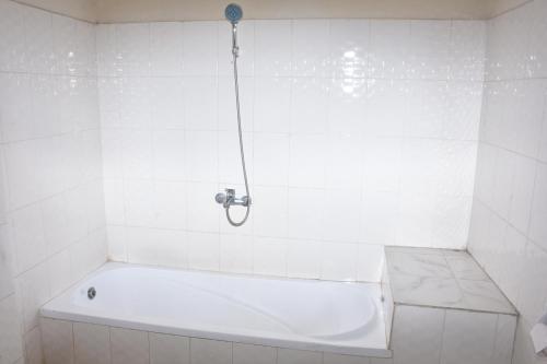 eine weiße Badewanne in einem weiß gefliesten Bad in der Unterkunft Torpedo Hotel in Lalībela