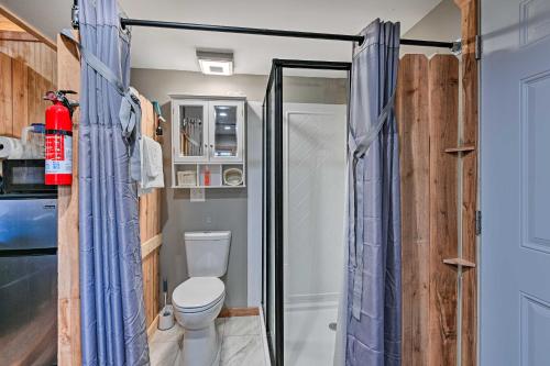 baño con aseo y ducha con cortinas azules en Tennessee Tiny Home about 24 Mi to Nashville, en Greenbrier