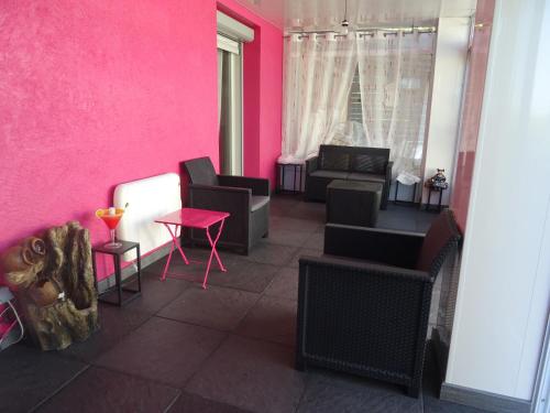 a living room with pink walls and chairs and a table at La Clef De Voute Amethyste in Saint-Genest