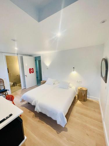 a white bedroom with a white bed and a desk at Hotel Cadario 1925 in Tebongo