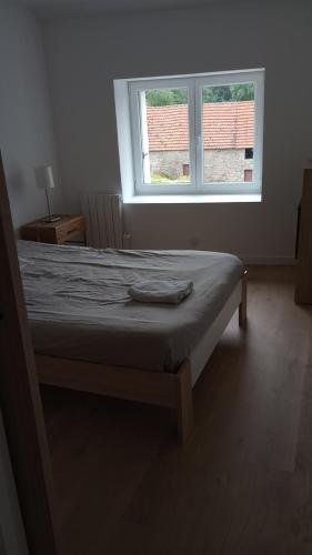 un lit dans une chambre avec une grande fenêtre dans l'établissement Logement avec tranquillité absolue, à Hamel ès Ronches