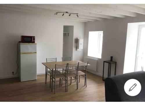 una sala da pranzo con tavolo, sedie e frigorifero di Logement avec tranquillité absolue a Hamel ès Ronches
