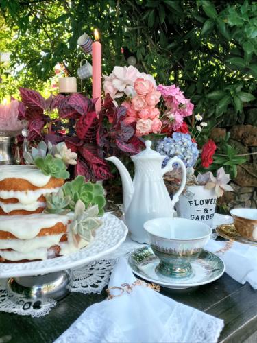 una mesa con un pastel y una vela y flores en La Petite France en Nova Petrópolis