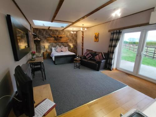 uma sala de estar com um sofá e uma cama em The Hideaway with hot tub em Chathill