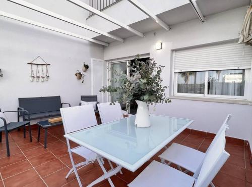 a dining room with a glass table and white chairs at SibsSanlucar Donana 1ª Línea Playa-Piscina-Padel in Sanlúcar de Barrameda