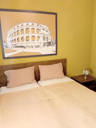 two beds in a room with a picture of the coliseum at Apartment Laura in Pula