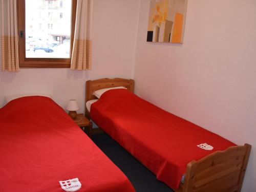 - 2 lits dans une petite chambre avec des draps rouges dans l'établissement Appartement cosy 4 pers avec balcon, centre de Pralognan, proche commerces et télécabine - FR-1-464-185, à Pralognan-la-Vanoise